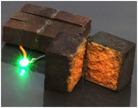 Fig.: A brick supercapacitor powering an LED light Photo: D'Arcy Laboratory/Washington University in St. Louis